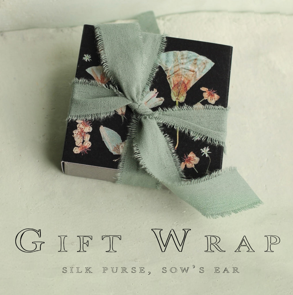 A gift wrapped in a black box with a green ribbon, featuring a floral design.